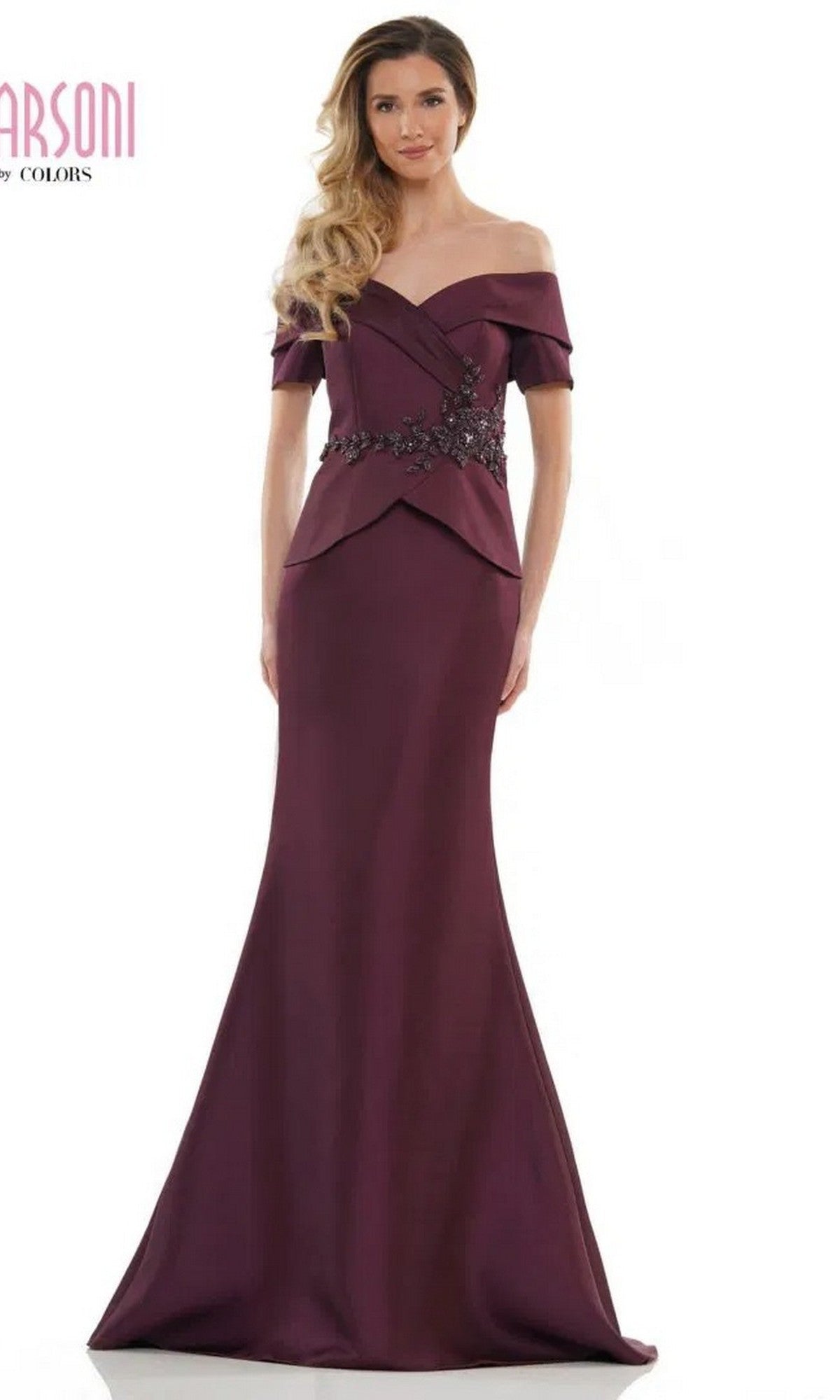 A woman poses against a white background in the Marsoni MV1144 long formal dress in wine, featuring an off-the-shoulder neckline, floor-length silhouette, and a beaded peplum accent at the waist.